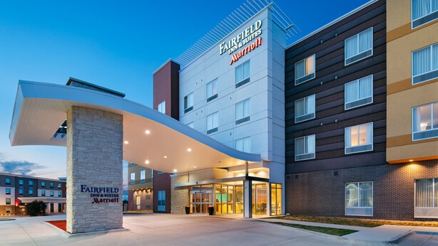 Un hotel Fairfield Inn & Suites Marriott con un diseño arquitectónico moderno, que cuenta con una entrada destacada y un cielo despejado.