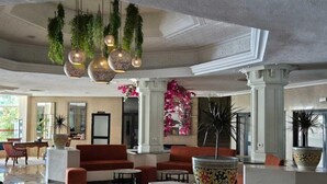 Eine großzügige Lobby mit roten Sitzgelegenheiten, hängenden Pflanzen und einer großen Dekorationsschale.