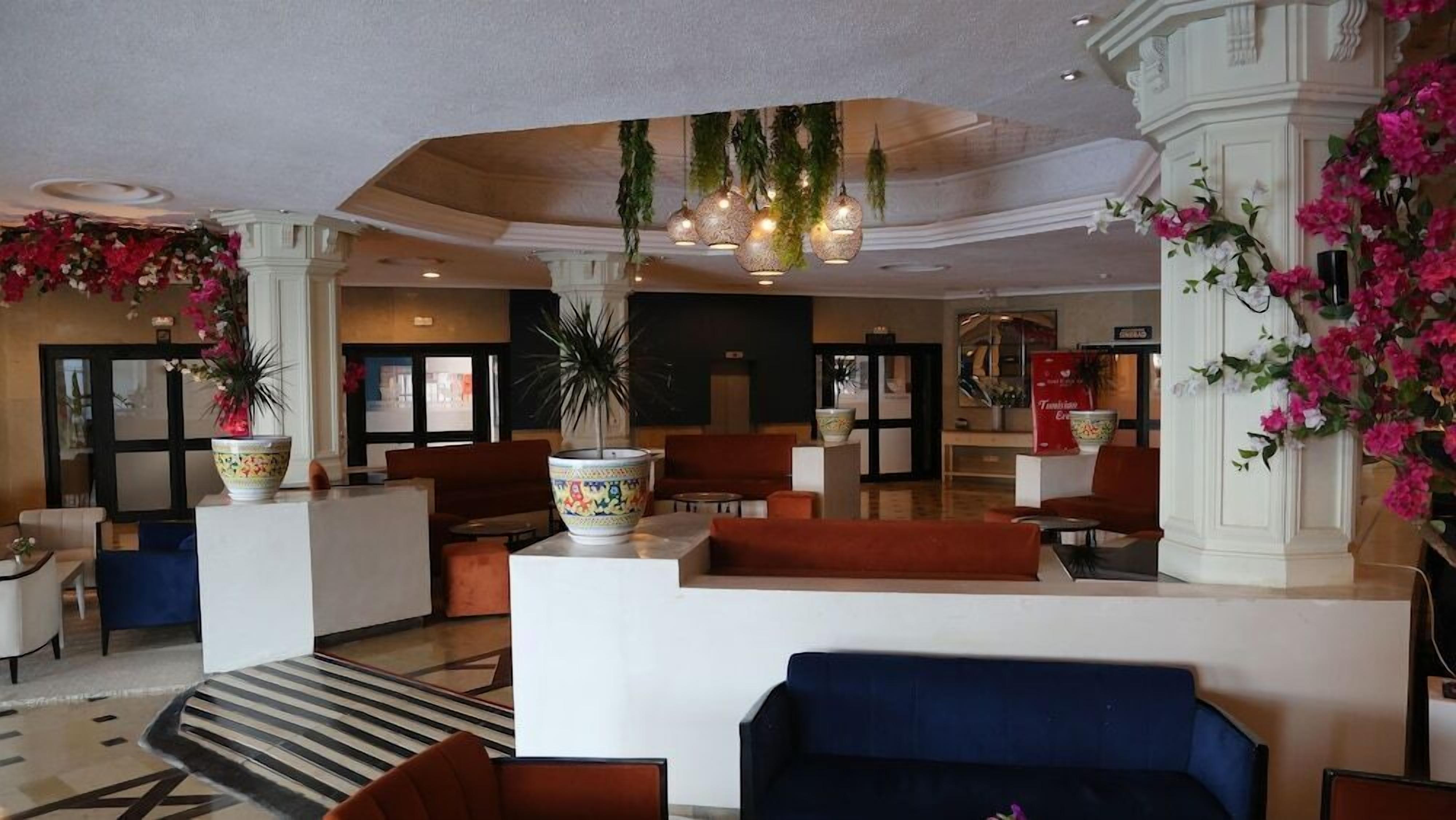 Un vestíbulo con zonas de estar, mostrador de recepción y plantas decorativas.