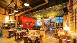 En restaurant med træborde og stole, et rødt køkkenområde og et loft med hængende grønt.
