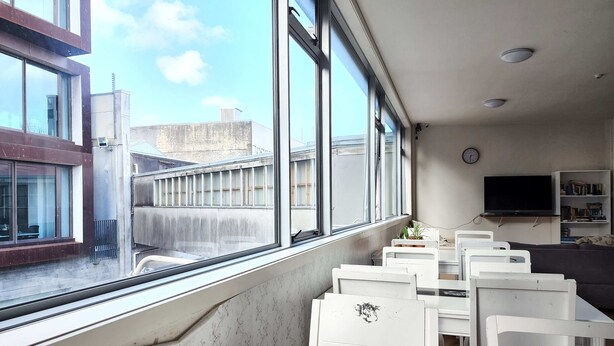 A room with large windows, a flat-screen TV, and a bookshelf. - Newton Lodge Auckland - Hostel (Auckland)