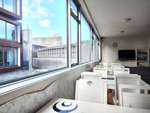 A room with large windows, a flat-screen TV, and a bookshelf. - Newton Lodge Auckland - Hostel (Auckland)