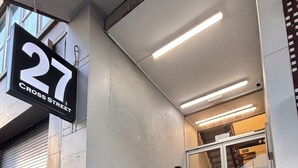 A staircase leading to an interior space, a sign indicating '27 CROSS STREET,' and a trash bin with graffiti. - Newton Lodge Auckland - Hostel (Auckland)