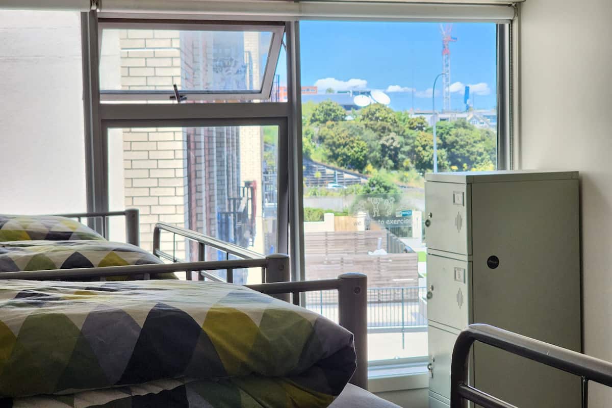 A room with a bed, a window, and a metal cabinet.