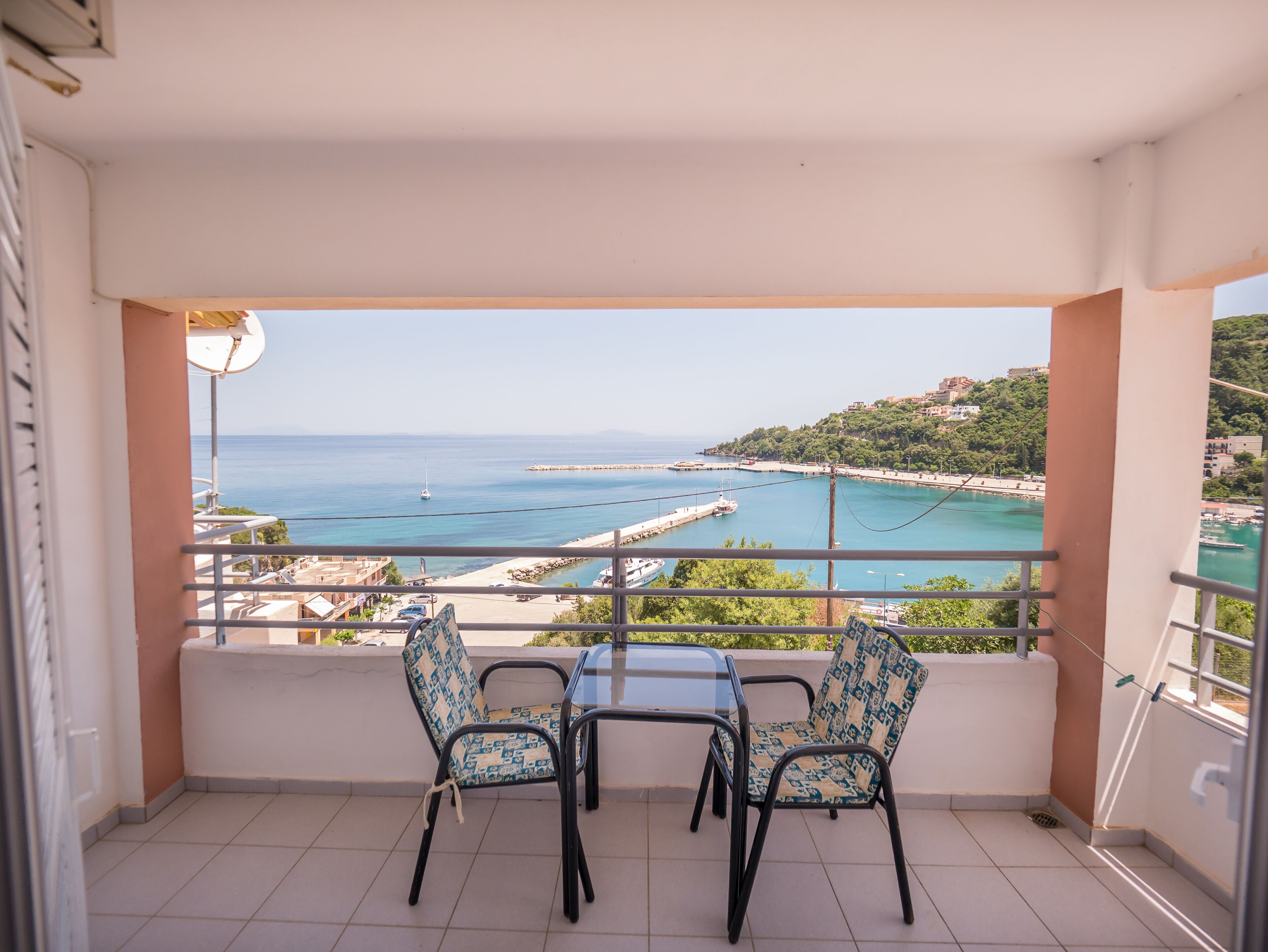Un balcon avec deux chaises et une table, offrant une vue sur la côte, avec une plage et une jetée.
