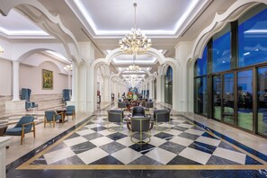Eine geräumige Lobby mit Schachbrettmuster-Boden, edlen Kronleuchtern und einer großzügigen Sitzecke.
