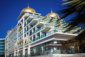 Ein mehrstöckiges Hotel mit Balkonen, großen Fenstern und goldenen Kuppeln.