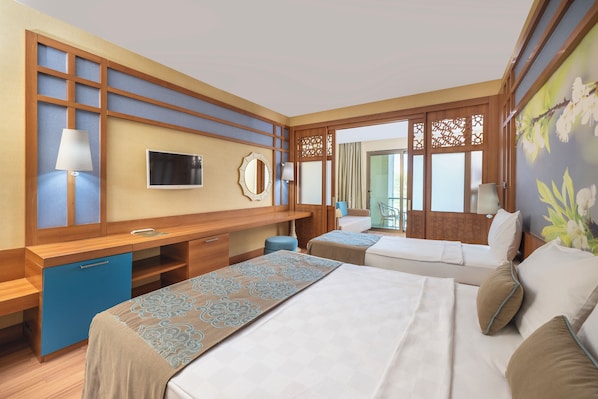 A hotel room with two beds, a desk, a TV, and a view of the outdoors.