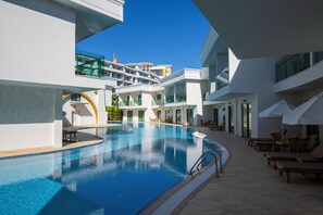 Un hotel moderno con una grande piscina interna, diversi balconi e lettini.