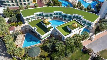 Ein modernes Hotel mit großem Pool, mehreren Balkonen und üppiger Bepflanzung.