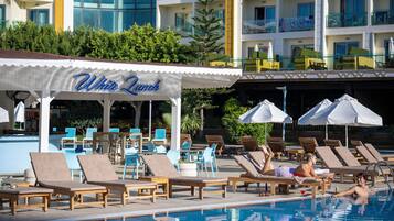 Ein Poolbereich mit Liegestühlen, Sonnenschirmen und einem Gebäude mit dem Schild "White Punch".