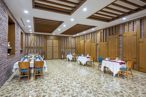 A dining area with multiple tables and chairs, wooden paneling on the walls, and a patterned floor.