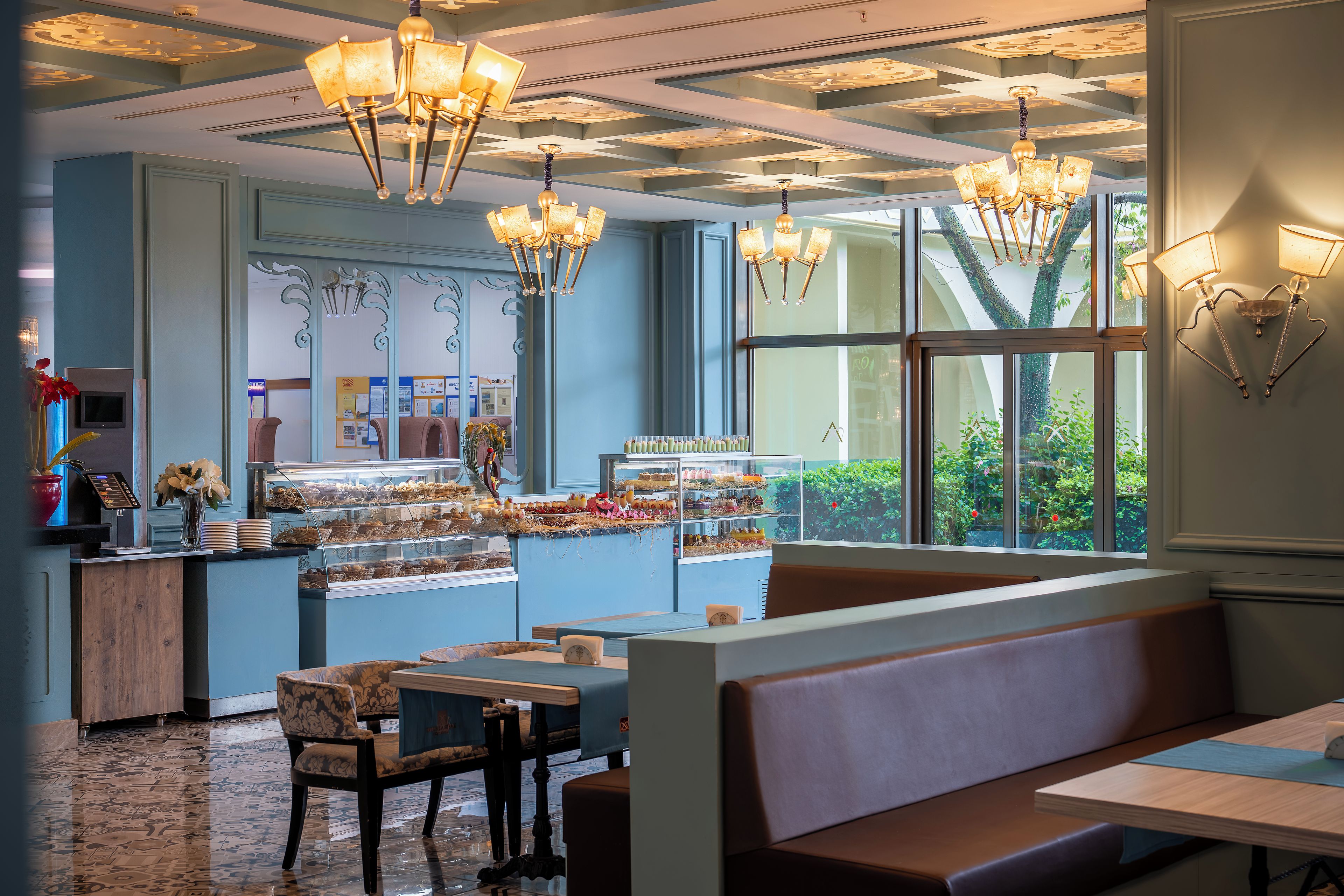 Ein Restaurant mit blauem Interieur, Holzmöbeln und einem großen Fenster mit Blick auf Grünflächen.