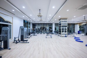 A modern gym with various exercise equipment, a central walking path, and a chandelier.