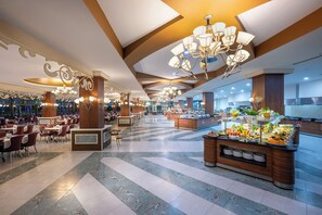 A spacious hotel lobby with multiple dining areas, a buffet, and a large chandelier. - Alan Xafira Deluxe Resort & Spa (Alanya)