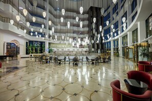 Um hall amplo com teto alto, várias áreas de estar e um balcão de recepção.