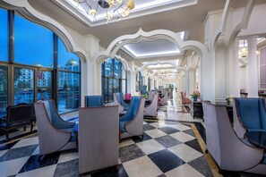 Un vestíbulo de hotel con suelo a cuadros, ventanas amplias y zonas de estar modernas.