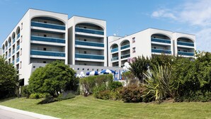 Een modern hotel met meerdere balkons en een verzorgd gazon.