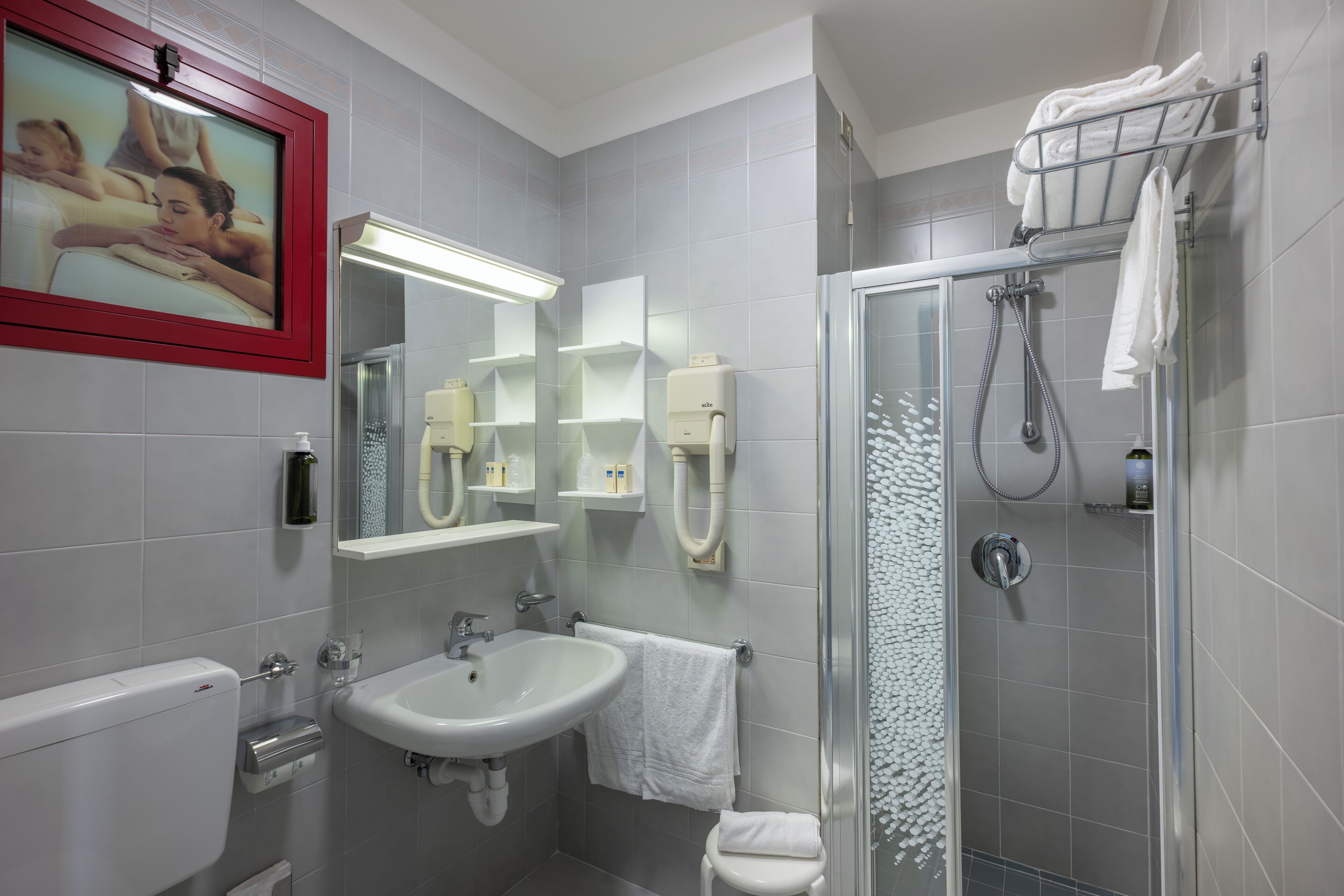 Un baño moderno con lavamanos, espejo, inodoro y ducha.
