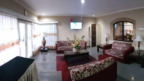 A hotel lobby with a sofa set, a coffee table, a TV mounted on the wall, and a mirror. - Hotel Scarlet Bukit Pakar (Bandung)