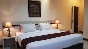 A hotel room with a large bed, two bedside lamps, a nightstand, a wardrobe, and a framed picture on the wall. - Hotel Scarlet Bukit Pakar (Bandung)