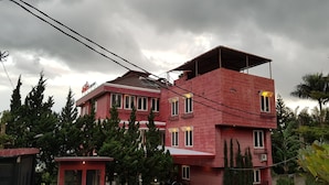 A multi-story building with a red facade, a gated entrance, and a small adjacent structure. - Hotel Scarlet Bukit Pakar (Bandung)