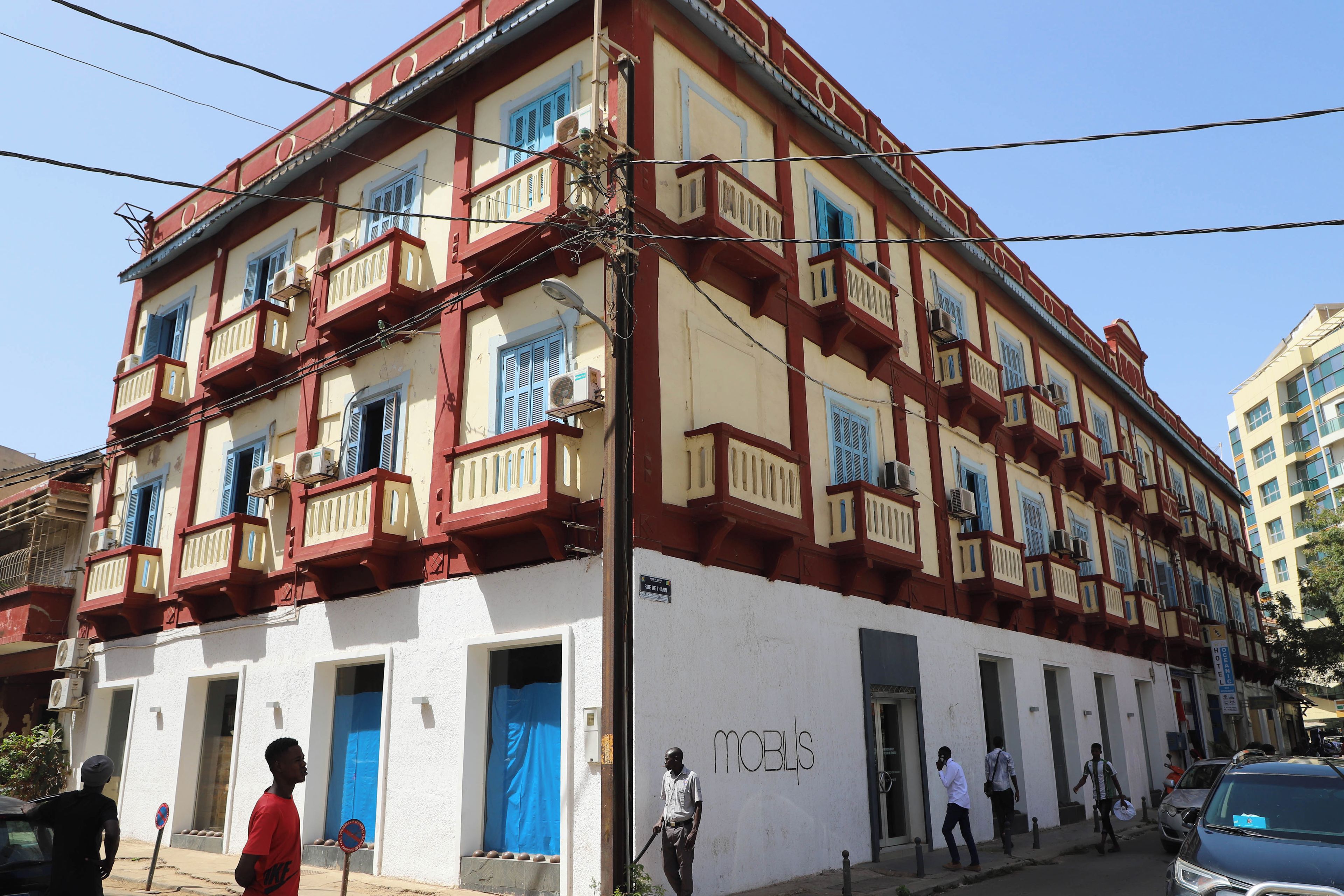 Un edificio de varios pisos con balcones, un letrero que dice 'MOBLIS' y una puerta azul.