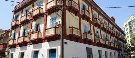 A multi-story building with balconies, a sign reading 'MOBLIS,' and a blue door.