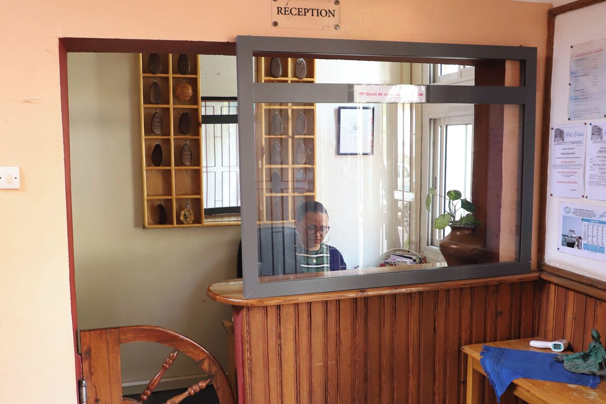A reception area with a wooden desk, a mirror, a wooden chair, and a reception sign.