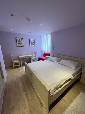 Un dormitorio con una cama, un escritorio, una silla y otra silla roja.