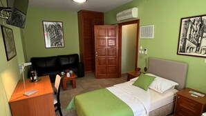 Une chambre avec deux lits, un bureau, une chaise, une télévision et des œuvres d’art accrochées aux murs.