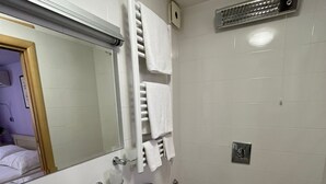 Une salle de bain équipée d’un lavabo, de toilettes, d’un porte-serviettes et d’un miroir.