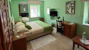 Une chambre avec un lit, un bureau, une chaise et un téléviseur.