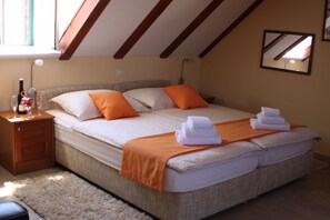 Quarto com uma cama grande, duas almofadas, mesa de cabeceira com garrafa e copos, e espelho na parede.