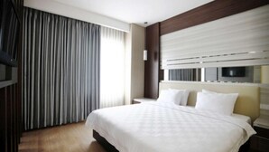 Une chambre d’hôtel avec un grand lit, une télévision et une fenêtre avec des rideaux.