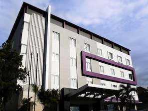 A multi-story building with a modern architectural design, featuring a combination of vertical and horizontal lines, and a mix of window sizes. - Hotel Harmoni Tasikmalaya (Tasikmalaya)