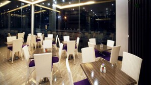 Un restaurant moderne avec des chaises blanches et des coussins violets, de grandes fenêtres et un plancher en bois.