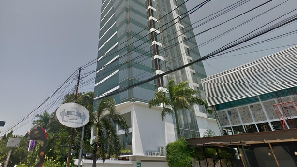 A tall, modern building with a glass facade and multiple balconies. - Hotel Apita Cirebon (West Cirebon)