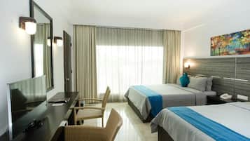 A hotel room with a bed, a desk with a chair, a television, and a painting on the wall.