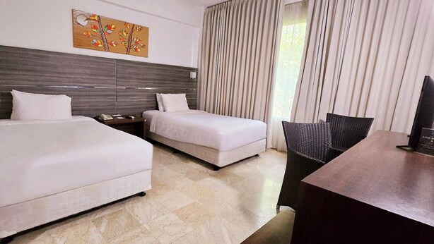 A hotel room with two beds, a desk, and a chair. - Hotel Apita Cirebon (West Cirebon)