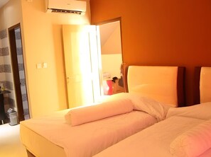 A hotel room with a bed, a mirror, and an air conditioning unit.
