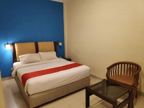 A hotel room with a bed, a chair, and a small table.