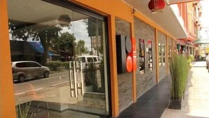 A hotel entrance with a glass facade, a red carpet, and a potted plant. - Pundi Rejeki Hotel (Jambi)