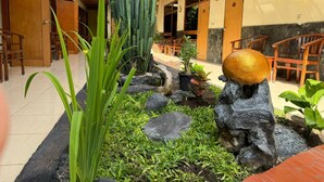 A hotel corridor with wooden doors, a cactus garden, and a rock feature. - Hotel Priangan (North Cirebon)