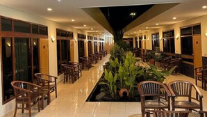 Vestíbulo de hotel con una fuente central, sillas de madera y un diseño de techo moderno.
