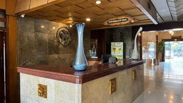 A reception desk with a marble counter, a large vase, and a sign that reads 'INFORMATION'.