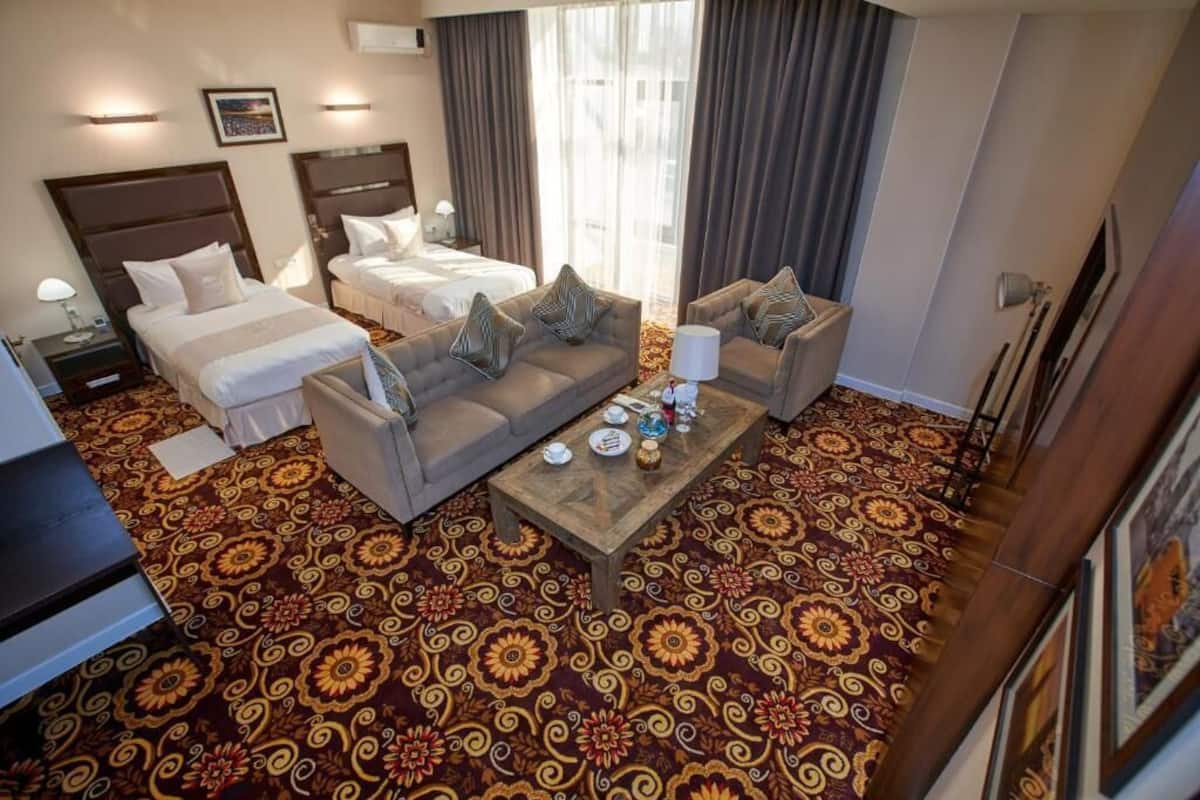Ein Hotelzimmer mit einem großen Bett, einer Couch, einem Couchtisch und einem gemusterten Teppich.