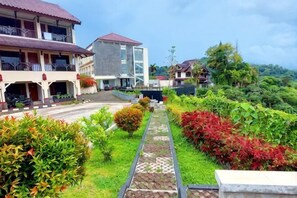 A hotel with a paved walkway, greenery, and buildings with balconies. - Sanggabuana Puncak Convention & Resort (Pacet)