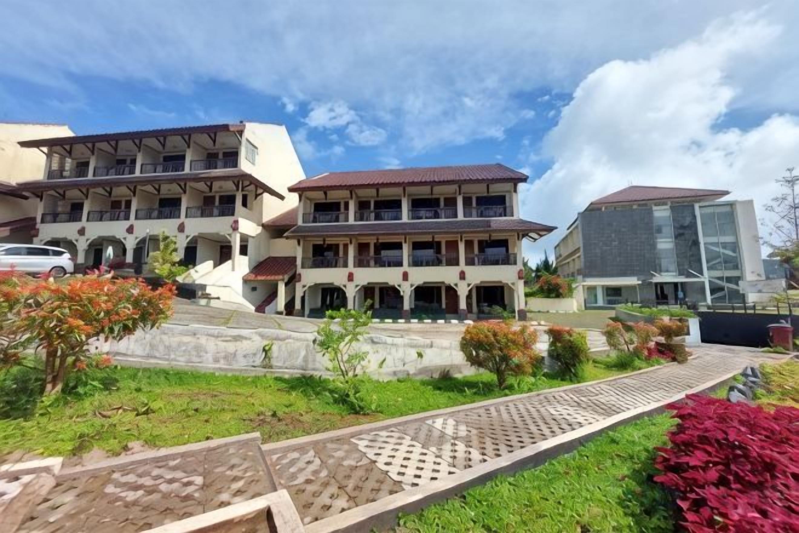 A multi-story building with a central courtyard, surrounded by greenery and a paved walkway.