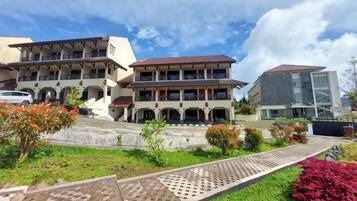 A multi-story building with a central courtyard, surrounded by greenery and a paved walkway.